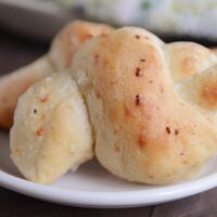 Two Parmesan breadstick knots on white plate.