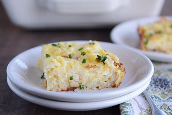 A piece of cheesy egg and hash brown casserole on a white plate.