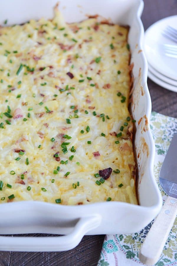 A white dish full of cheesy egg casserole sprinkled with green onion. 