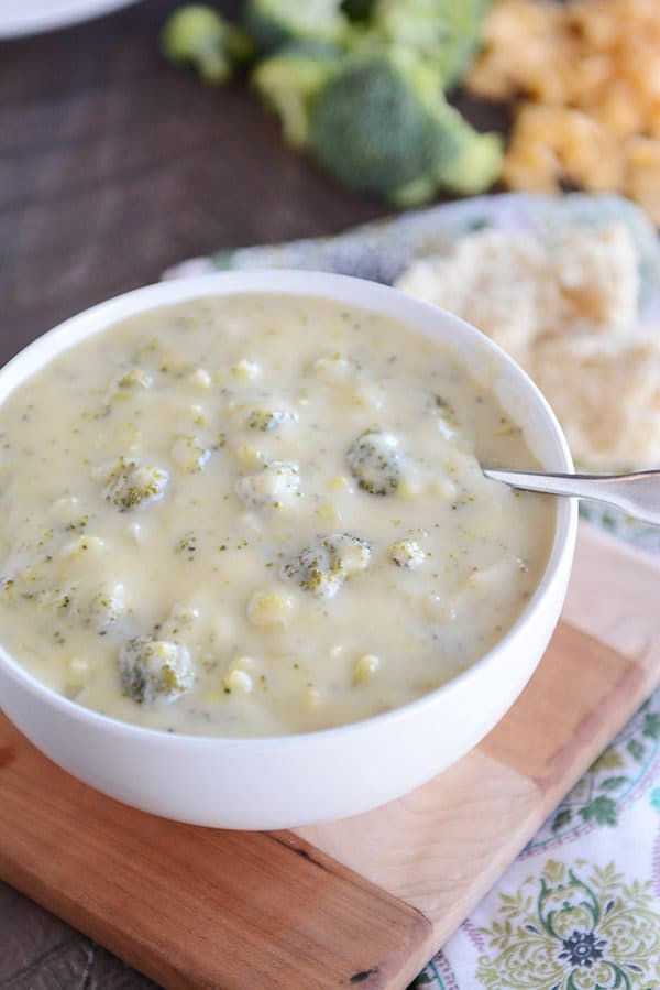 Spoon in white bowl filled with homemade broccoli cheese soup.