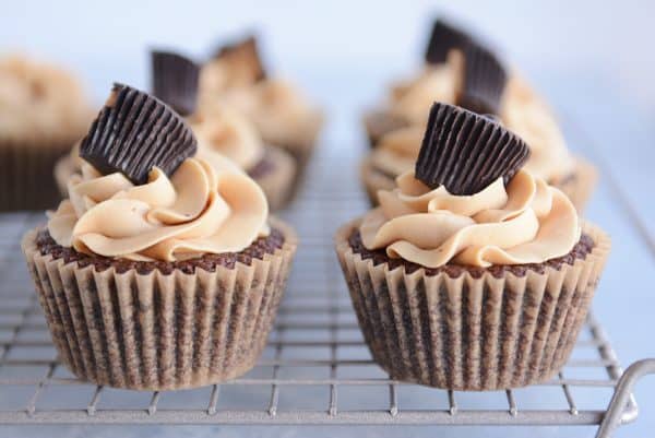 Side by side fudgy brownie cupcakes with the best peanut butter frosting and topped with a peanut butter cup.