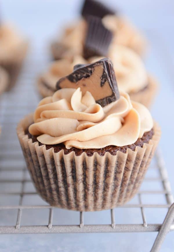 Fudgy brownie cupcake with the best peanut butter frosting swirled on top and garnished with half of a peanut butter cup.