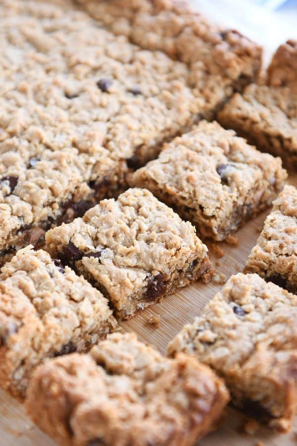 Slab of monster cookie bars cut into squares on wood board.