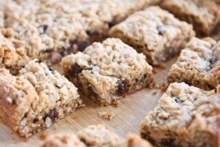 Slab of monster cookie bars cut into squares on wood board.