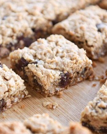 Slab of monster cookie bars cut into squares on wood board.