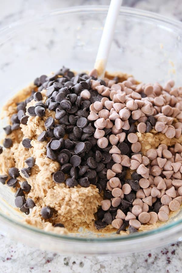 Bowl of monster cookie dough with chocolate chips and butterscotch chips about to be mixed in.