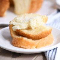 Stack of buttery pull apart bundt bread pieces on white plate.
