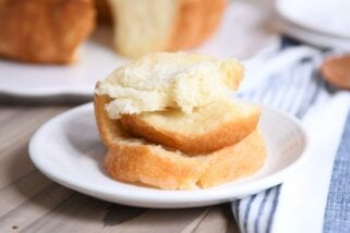 Stack of buttery pull apart bundt bread pieces on white plate.