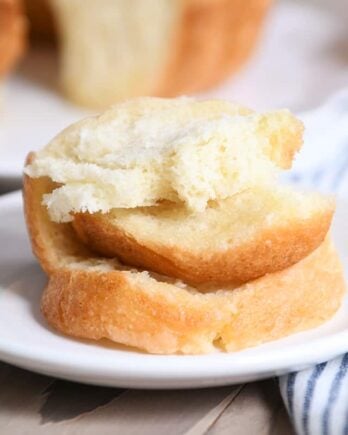 Stack of buttery pull apart bundt bread pieces on white plate.