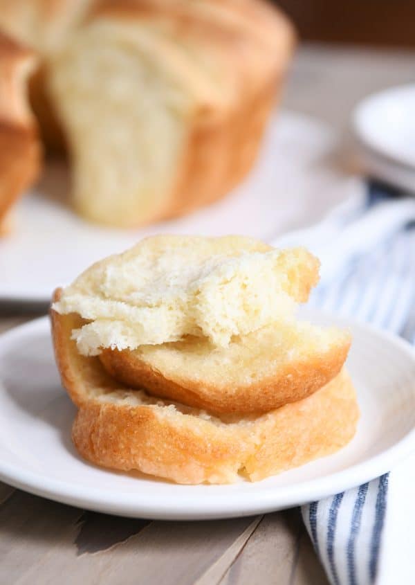 Stack of buttery pull apart bundt bread pieces on white plate. 