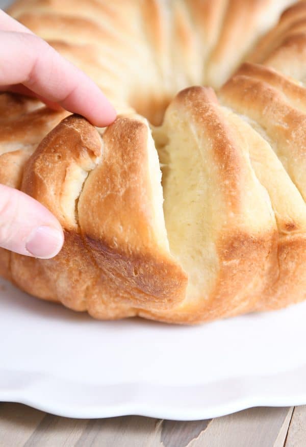 Someone pulling off a piece of a loaf of buttery bundt bread.