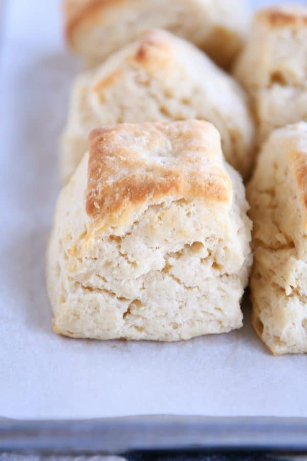 Several super flaky buttermilk biscuits on white platter.