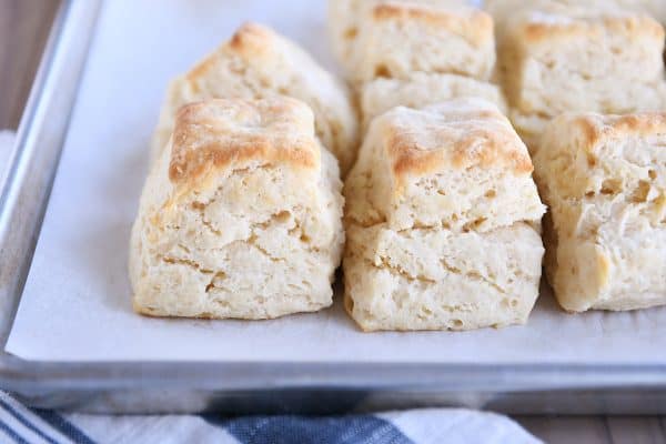 Several super flaky buttermilk biscuits on white platter.