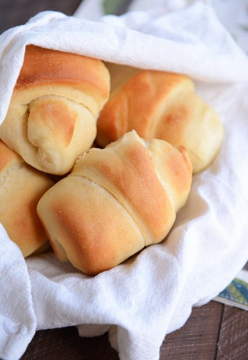 A basket full of golden brown baked rolls. 