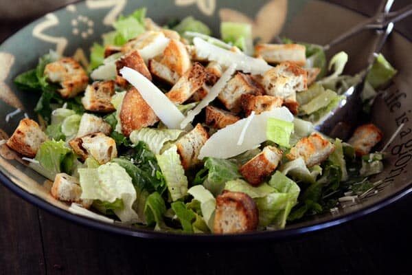 A large bowl full of caesar salad without dressing. 