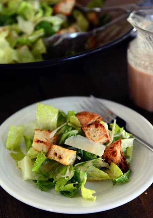 A white plate of caesar salad without dressing. 