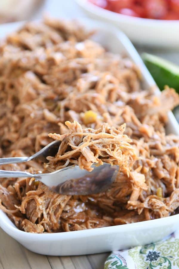 Copycat sweet pork in white tray with a scoop being lifted with tongs.