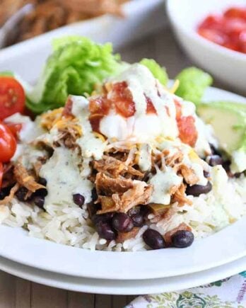 White plate with cilantro lime rice, black beans, sweet pork and toppings.