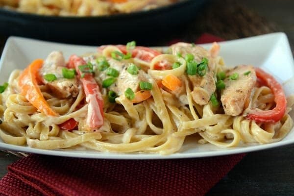 A white platter of cajun chicken pasta. 