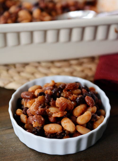 A small white ramekin filled with bacon-filled baked beans.