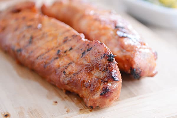 Two grilled pork tenderloins on a wooden cutting board.