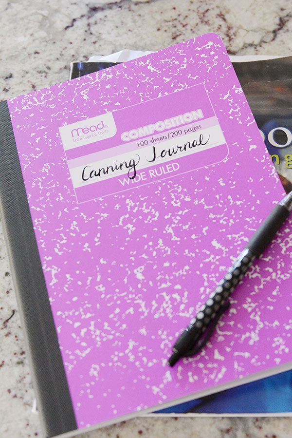 a purple notebook that says Canning Journal on it with a pen laying on top.