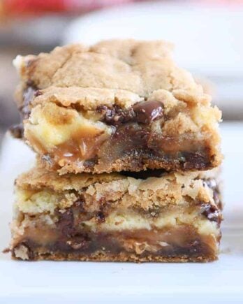 Two caramel cheesecake stuffed chocolate chip cookie bars stacked.