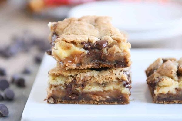 Two caramel cheesecake stuffed chocolate chip cookie bars stacked.