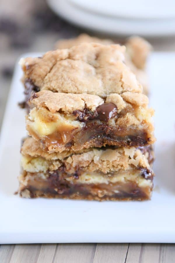 Two caramel cheesecake stuffed chocolate chip cookie bars stacked. 