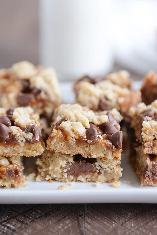 Squares of cut up caramel chocolate chip cookie bars on a white platter.