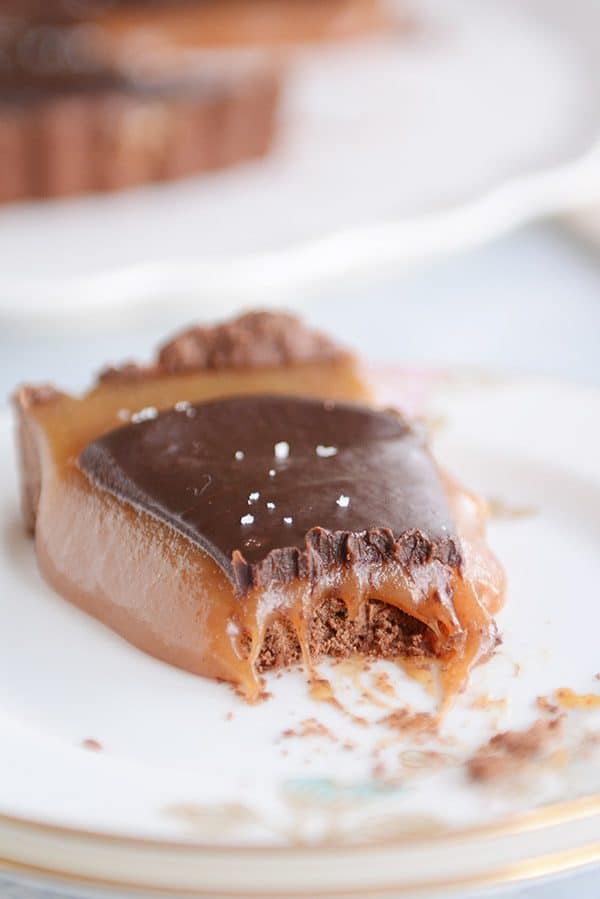 A slice of chocolate caramel tart with a bite taken out. 