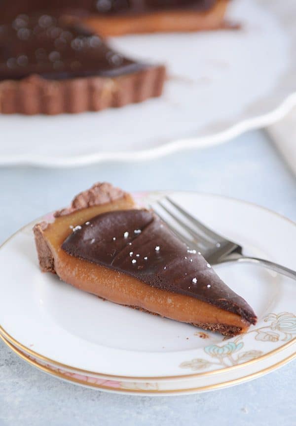 A slice of chocolate caramel tart on a white plate.