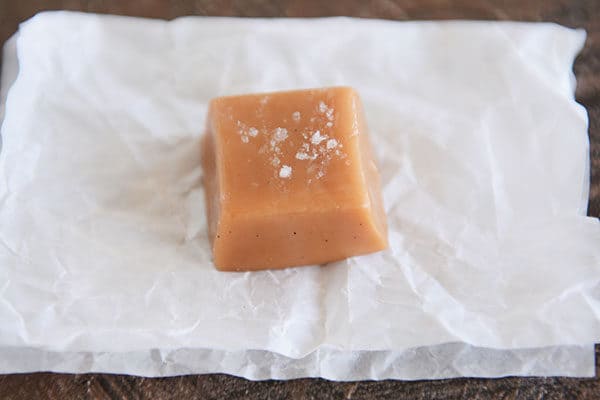 A square of salted vanilla bean caramel on a piece of parchment.