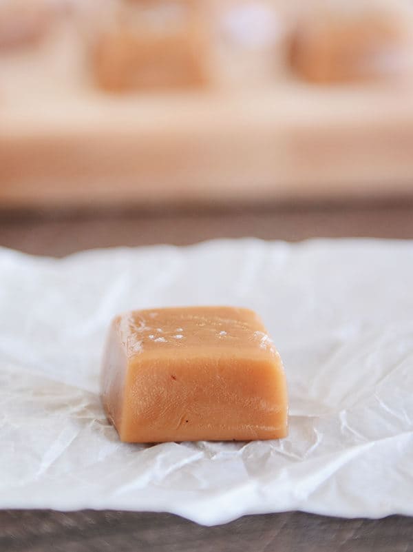 An unwrapped salted vanilla bean caramel on a piece of parchment.