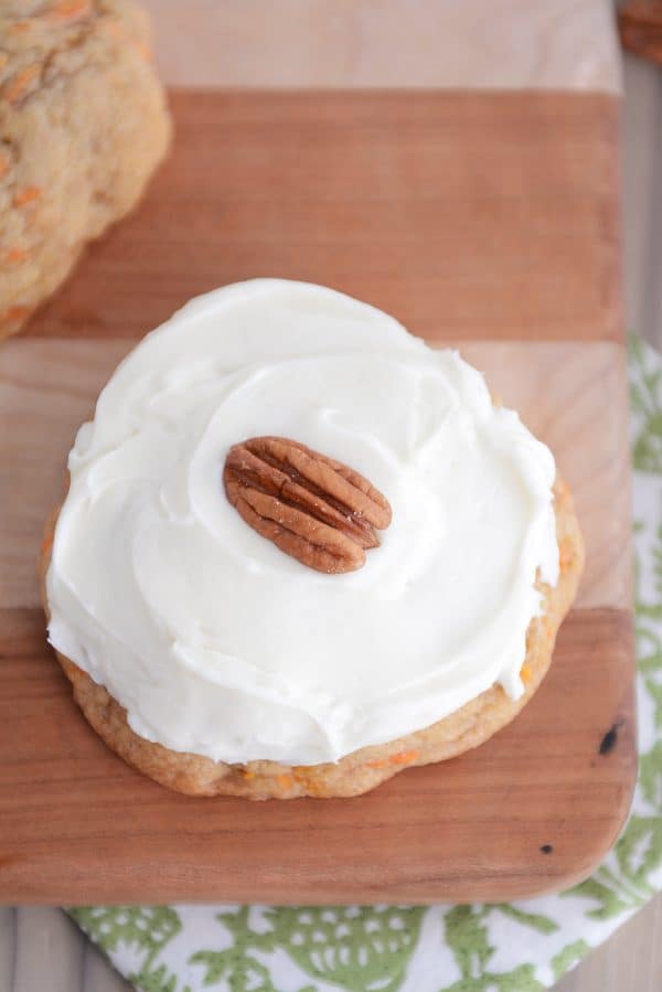 Top down shot of a frosted carrot cake cookie with pecan on top.