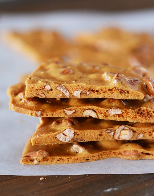 stacked maple cashew brittle pieces on a piece of parchment paper