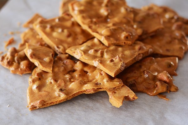 Pieces of maple cashew brittle broken apart on a piece of parchment paper.