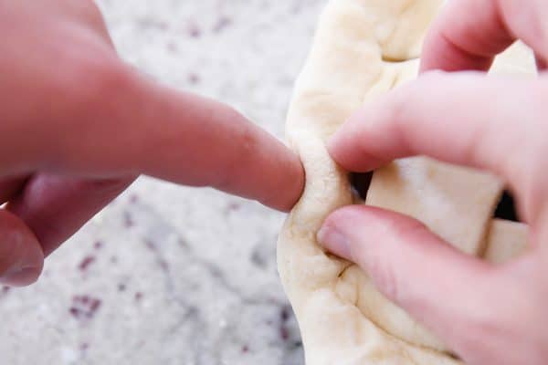 Fluting the edge of cherry pie crust.