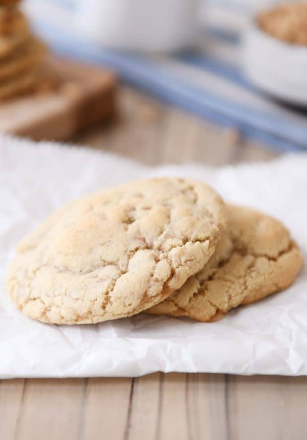 Two thin toffee cookies stacked on a piece of parchment.