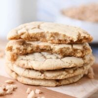 Stack of toffee cookies on wood cutting board with one cookie broken in half.