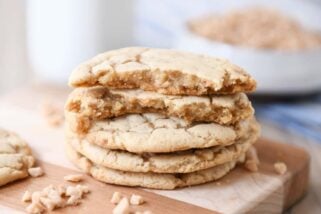 Stack of toffee cookies on wood cutting board with one cookie broken in half.