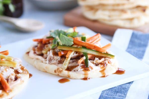 Chicken banh mi flatbread with pickled cucumbers and carrots on white platter.