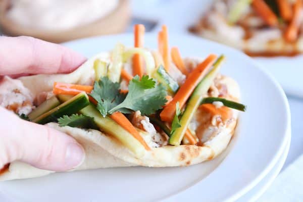 Folded chicken banh mi flatbread like a taco ready to eat on white plate.