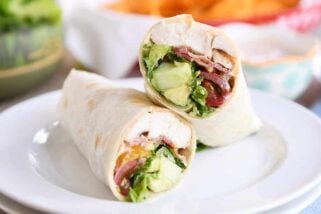 Chicken BLT burritos cut in half on white plate.