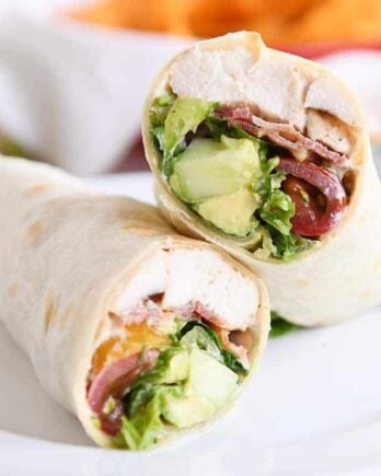 Chicken BLT burritos cut in half on white plate.