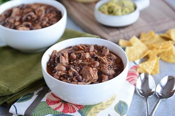 Two white bowls full of black bean chicken chili. 