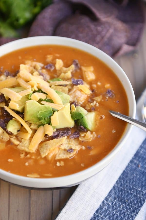 Chicken enchilada soup in tan bowl with brown stripe.