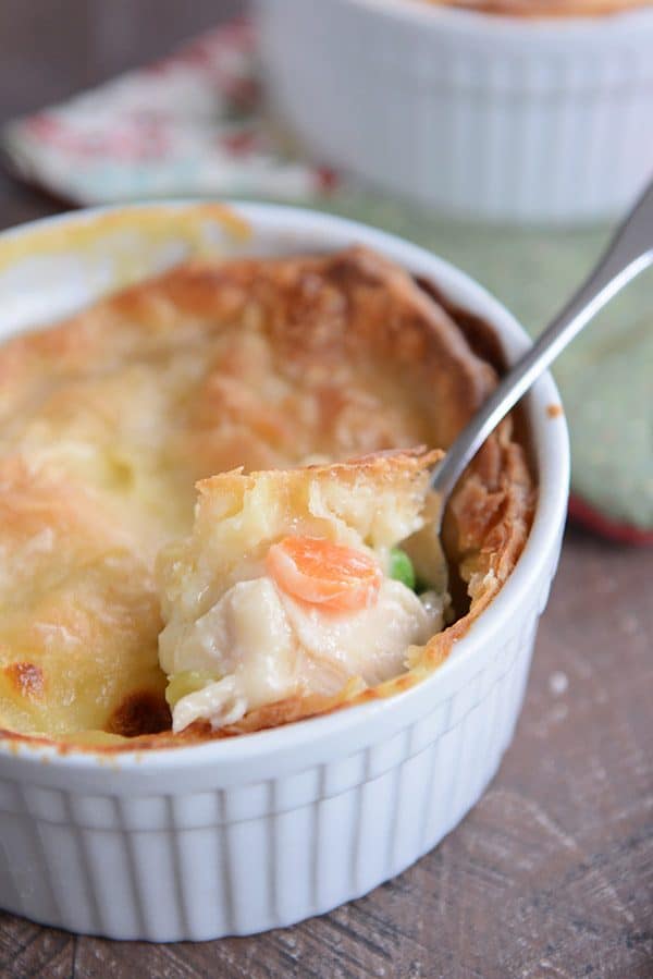 a white ramekin with chicken pot pie and a spoon taking a bite out