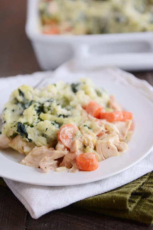 A creamy chicken and vegetable mixture next to kale-filled mashed potatoes.