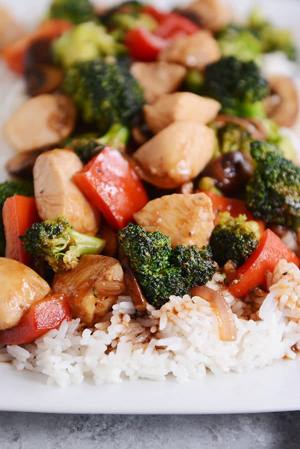 Chicken and vegetable stir-fry over cooked white rice. 